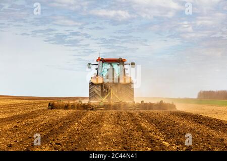 Rückansicht des Bauern im Traktor Pflügefeld im Frühjahr Stockfoto