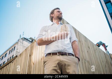 Geschäftsmann hält Holzhaus Modell auf Baustelle in der Stadt Stockfoto