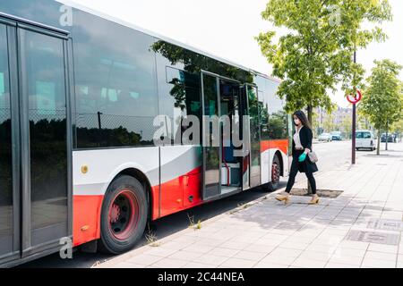 Junge Frau mit Schutzmaske und Handschuhen in öffentlichen Bus, Spanien Stockfoto