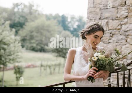 Junge lächelnde Frau in eleganten Brautkleid und Bouquet Stockfoto