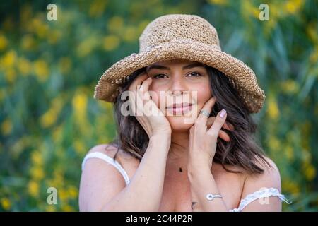 Porträt einer lächelnden, jungen Frau, die ihr Gesicht berührt, Alicante, Provinz Alicante, Spanien Stockfoto