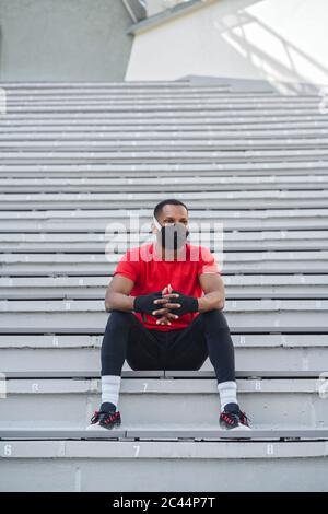 Sportler mit Gesichtsmaske auf der Treppe sitzen Stockfoto