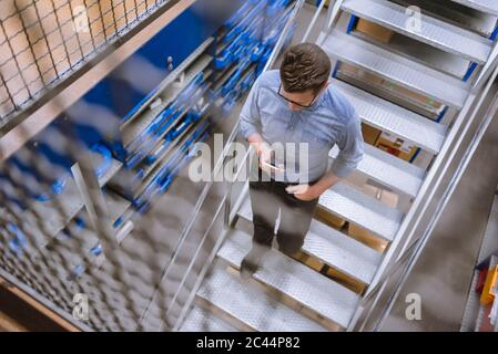 Geschäftsmann mit Smartphone in einer Fabrik die Treppe hinunter Stockfoto