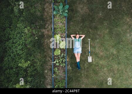 Luftaufnahme der Frau, die am Hochbett auf dem Land im Hof liegt Stockfoto