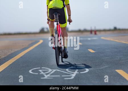 Fahrradfahrer auf der Straße in der Wüste in Dubai, Vereinigte Arabische Emirate Stockfoto