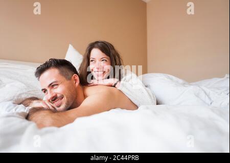 Nachdenkliches junges Paar, das zu Hause im Bett liegt Stockfoto