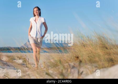 Portrait einer lächelnden Frau, die in den Dünen am Strand läuft, Sardinien, Italien Stockfoto