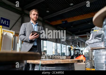 Junger Geschäftsmann mit Tablet in einer Fabrik Stockfoto