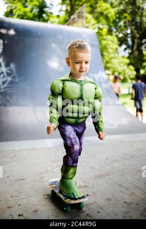 Junge mit einem Skate in einem Skatepark. In einem Superhelden Kostüm. Stockfoto