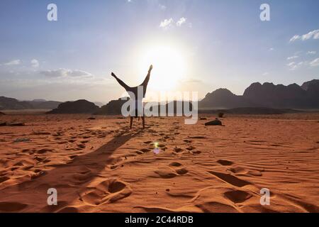 Frau, die einen Handstand auf der roten Sandwüste in der Wadi Rum Wüste, Jordanien macht Stockfoto