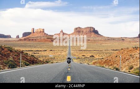 Mann, der Motorrad auf der Wüstenstraße reitet, Monument Valley Tribal Park, Utah, USA Stockfoto