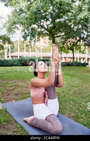 Frau mittleren Erwachsenen Yoga auf Matte im Park üben Stockfoto