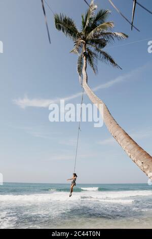 Volle Länge des Frau Schwingen von Palme am Strand gegen Himmel, Sri Lanka Stockfoto