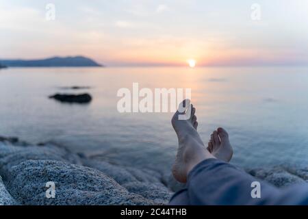 Spanien, Costa Brava, die Beine der Frau liegen am Strand bei Sonnenaufgang Stockfoto