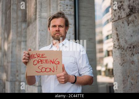 Ladenbesitzer hält Pappe mit Öffnungsansage in der Stadt Stockfoto