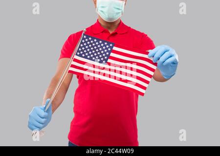 Lieferung Mann hält amerikanische Flagge Nahaufnahme Tragen medizinische Maske und Handschuhe. Indischer Retter mit USA Flagge in Händen. Zustelljunge isoliert Stockfoto