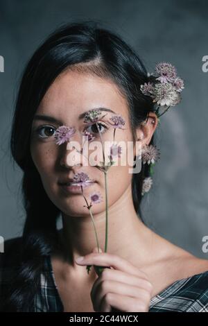 Schöne junge Frau, die Blumen hält und trägt Stockfoto