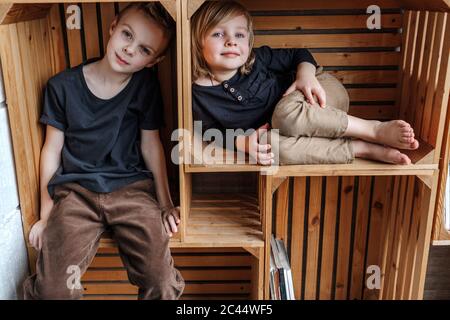 Portrait von Jungen, die in Holzkisten sitzen Stockfoto