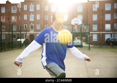 Reifer Mann spielt mit Fußball auf dem Fußballplatz in der Stadt Stockfoto