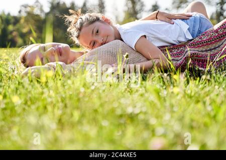 Nettes Mädchen liegen auf Mutter während der Entspannung während sonnigen Tag Stockfoto