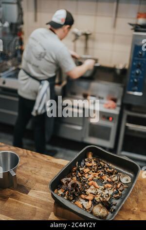 Nahaufnahme von gerösteten Speisen im Behälter auf der Theke gegen Koch Kochen im Restaurant Stockfoto