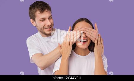 Kerl, der die Augen seiner Frau von hinten bedeckt Stockfoto