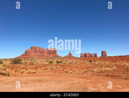 Tolle Aussicht auf Monument Valley mit roter Wüste und blauem Himmel und Wolken am Morgen. Monument Valley in Arizona mit West Mitten Butte, East Mitten Stockfoto