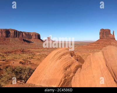 Tolle Aussicht auf Monument Valley mit roter Wüste und blauem Himmel und Wolken am Morgen. Monument Valley in Arizona mit West Mitten Butte, East Mitten Stockfoto