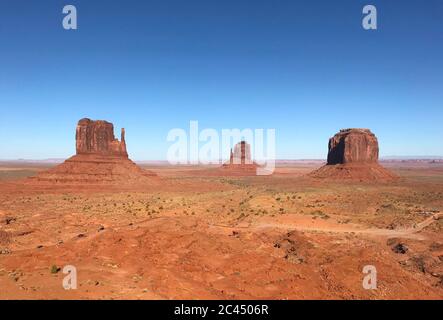 Tolle Aussicht auf Monument Valley mit roter Wüste und blauem Himmel und Wolken am Morgen. Monument Valley in Arizona mit West Mitten Butte, East Mitten Stockfoto