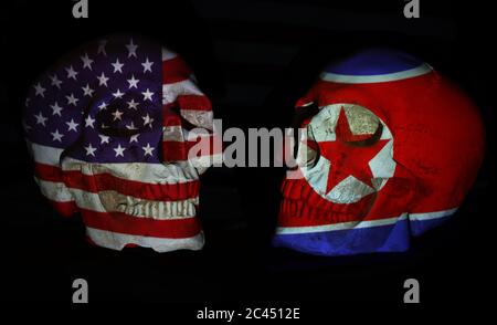 Amerikanische oder US- und nordkoreanische Flaggen projizierten sich über zwei realistisch aussehende weiße Schädel. Isoliert vor einem schlichten schwarzen Hintergrund. Stockfoto