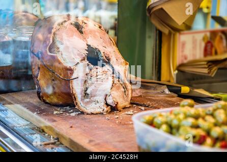 Das traditionelle Schweinefleisch von Ariccia auf dem Tresen eines Straßenverkäufers (italienisches Essen). Eine Frau schneidet das Schweinefleisch, um ein Sandwich zu machen. Frascati, Ariccia, Rom, Stockfoto