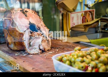 Das traditionelle Schweinefleisch von Ariccia auf dem Tresen eines Straßenverkäufers (italienisches Essen). Eine Frau schneidet das Schweinefleisch, um ein Sandwich zu machen. Frascati, Ariccia, Rom, Stockfoto