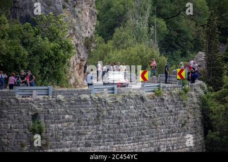 Skradin Kroatien, Juni 2020 Rot und schwarz Mitsubishi Lancer Abstieg vom Hügel während eines Rennens, aus der Ferne gesehen, versammelten sich die Menschen entlang der Straße Stockfoto