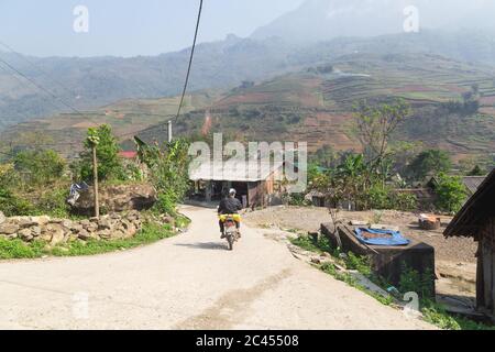 SAPA, VIETNAM - 23. MÄRZ 2017: Straßen in Dörfern von Sapa Vietnam. Hütten, Hügel und eine Person auf einem Motorrad zu sehen. Motorräder sind ein gängiger Weg t Stockfoto