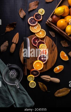 Vertikale High-Angle-Aufnahme von Scheiben von Orange und Zitrone Und eine Schachtel Zitrone und Orangen auf einem Tisch Stockfoto