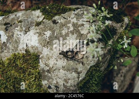 Eheringe und Verlobungsring auf einer Steinoberfläche. Stockfoto