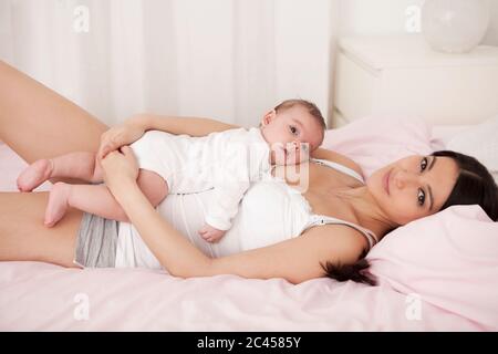 Mutter liegt im Bett mit Baby Stockfoto