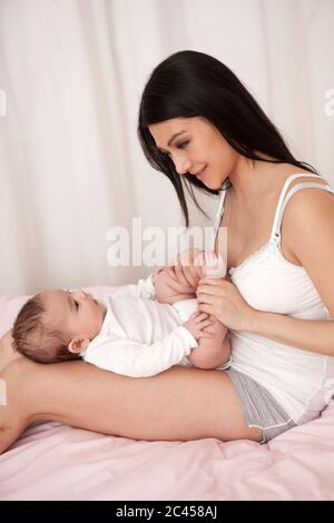 Mutter spielt mit Baby im Bett Stockfoto