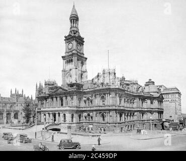 Sydney Australien 1938: Das Rathaus von Sydney in der Vorkriegszeit Sydney mit der St Andrews Cathedral auf der linken Seite. Merkwürdigerweise scheinen in der linken unteren Ecke zwei Männer eine Art Nahaufnahme (möglicherweise erhitzt) zu führen. Dieses Bild wurde 1938 in einem Buch des Gemeinderats von Sydney veröffentlicht, um "den 150. Jahrestag der Gründung einer Nation" zu gedenken. Stockfoto