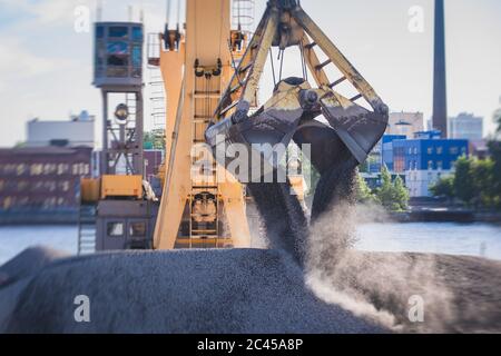 Bulk-Handling-Kran Entladen Sand, Straße Metall und Kies von Frachtschiff, schwere Fahrzeug und Portalkran Lader arbeiten mit Schüttgütern in Stockfoto