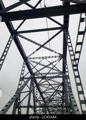 Metallkonstruktion der Eisenbahnbrücke mit dem aufsteigenden Mittelteil für die Durchfahrt von Schiffen. Blick von unten vom Fenster des Autos. Architektur, Designelemente Stockfoto