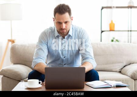 Kerl hört Musik online und mit Laptop Stockfoto