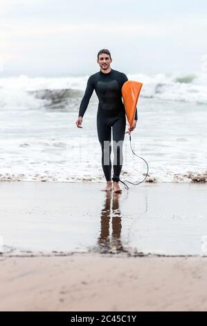 Surfer kommt aus dem Meer, Tamraght, Marokko Stockfoto