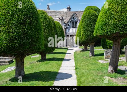 St Marys Kirche lychgate und Eibenbäume im Sonnenlicht. Painswick, Cotswolds, Gloucestershire, England Stockfoto