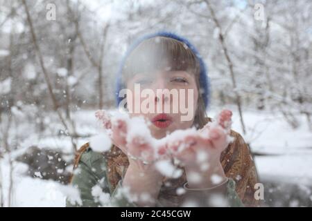 Junge Frau bläst Schnee aus ihrer Hand Stockfoto