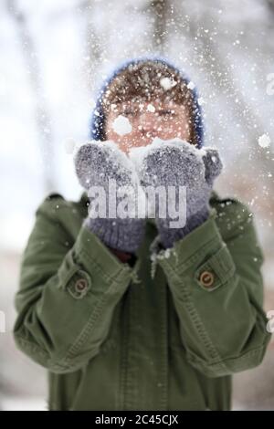 Junge Frau bläst Schnee aus ihrer Hand Stockfoto