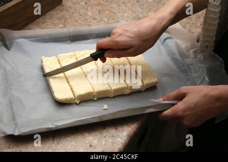 Kokosnussquadrate auf einem Ofenblech, das schließlich mit Schokolade bedeckt wird. Stockfoto