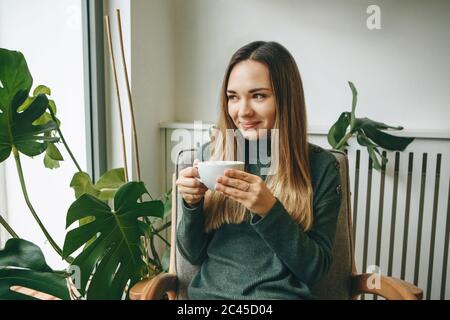 Ein Mädchen sitzt in einem Café und trinkt ein heißes Getränk. Sie wartet auf jemanden, und sie hat eine Sitzung oder genießt ihr Morgen trinken. Stockfoto