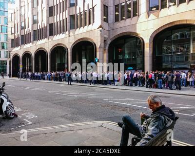 LONDON, GROSSBRITANNIEN - 04. Mai 2008: Ein Bettler trinkt allein auf einer Straße in der Stadt, während eine große Anzahl von Mitarbeitern im Banken- und Finanzwesen trinken Stockfoto