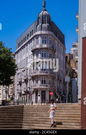 Porto, Portugal - EINE Frau, die auf Steintreppen vor einem wunderschönen neoklassischen Steingebäude mit ornaierten Balkonen geht Stockfoto